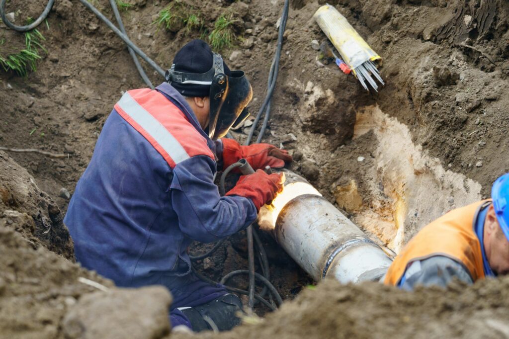 Utility worker fixing broken water main. Sewerage pipe repair concept. Top view.